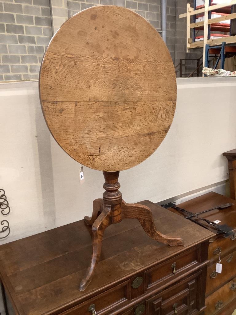 A George III faded oak circular tilt top tea table, 68cm diameter, height 72cm